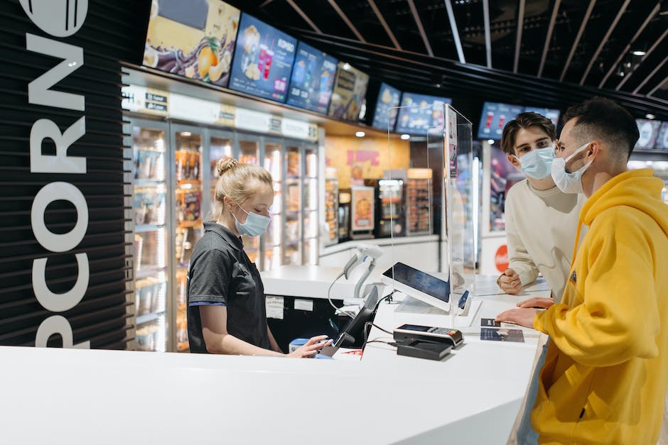 An image of a cashier processing a transaction at a checkout counter with a line of customers waiting